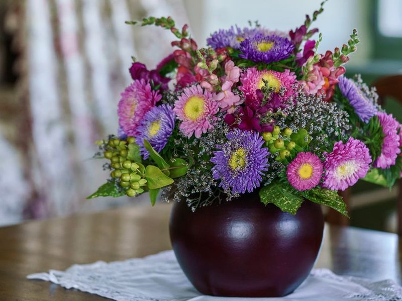 Ramo de flores rosadas y lilas en un florero